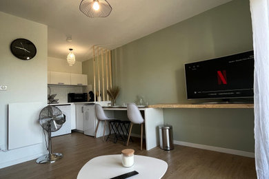 Foto de salón abierto minimalista de tamaño medio sin chimenea con paredes verdes, suelo de madera clara y televisor independiente