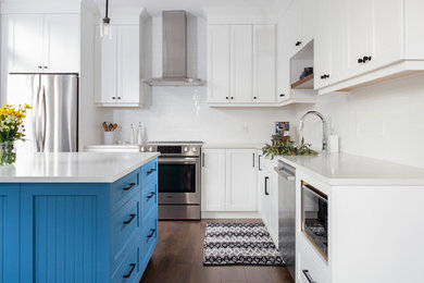 Inspiration for a mid-sized country l-shaped kitchen in Vancouver with shaker cabinets, white cabinets, white splashback, subway tile splashback, stainless steel appliances, dark hardwood floors and with island.