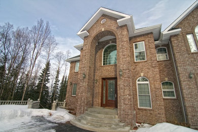 Inspiration for a large timeless red three-story brick exterior home remodel in Other