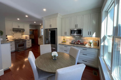 Mid-sized elegant l-shaped medium tone wood floor eat-in kitchen photo in Boston with an undermount sink, shaker cabinets, white cabinets, granite countertops, beige backsplash, subway tile backsplash, stainless steel appliances and no island