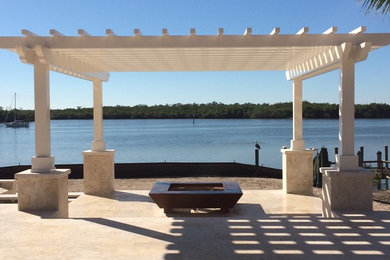 Example of a huge patio design in Miami with a fire pit and a pergola