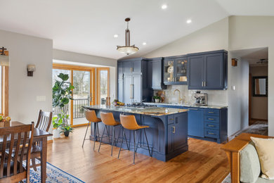 This is an example of a mid-sized transitional single-wall eat-in kitchen in Minneapolis with a double-bowl sink, shaker cabinets, blue cabinets, granite benchtops, beige splashback, ceramic splashback, stainless steel appliances, medium hardwood floors, with island, multi-coloured benchtop and vaulted.