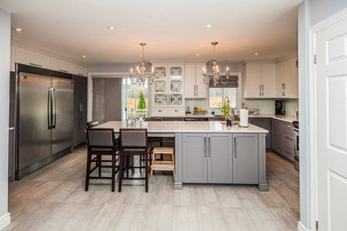 Example of a mid-sized classic l-shaped concrete floor enclosed kitchen design in Montreal with a double-bowl sink, glass-front cabinets, white cabinets, granite countertops, black backsplash, subway tile backsplash, stainless steel appliances and an island