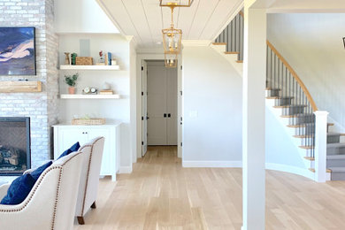 Large farmhouse open concept light wood floor family room photo in Other with gray walls, a standard fireplace, a brick fireplace and a wall-mounted tv