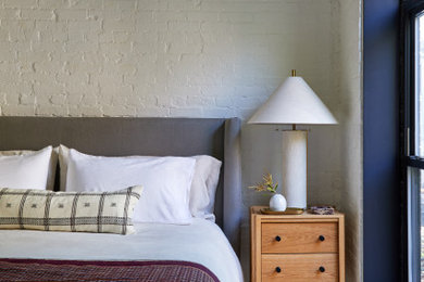 Modelo de dormitorio vintage pequeño con paredes blancas, suelo de madera en tonos medios, suelo marrón y ladrillo
