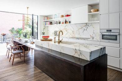 This is an example of a large contemporary galley eat-in kitchen in New York with an integrated sink, flat-panel cabinets, white cabinets, white splashback, marble splashback, panelled appliances, dark hardwood floors, with island, brown floor, marble benchtops and white benchtop.