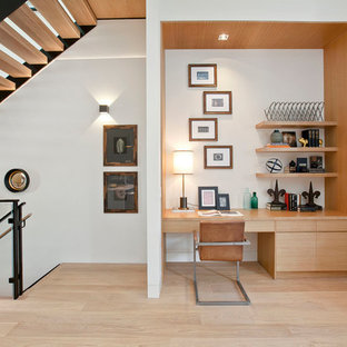 Photo of a modern home office and library in San Francisco with white walls, light hardwood flooring and a built-in desk.