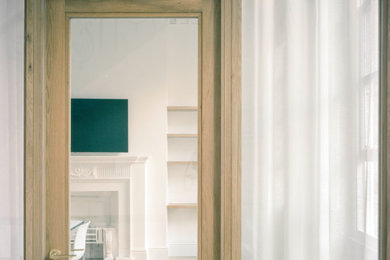 Design ideas for a medium sized contemporary study in London with white walls, light hardwood flooring, a standard fireplace, a stone fireplace surround, a freestanding desk, beige floors and a feature wall.