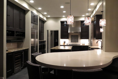 Eat-in kitchen - mid-sized transitional u-shaped slate floor eat-in kitchen idea in Indianapolis with brown cabinets, stainless steel appliances, shaker cabinets, solid surface countertops, white backsplash, two islands, a farmhouse sink and stone tile backsplash