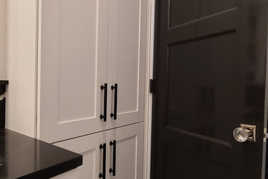 Example of a large trendy master white tile and marble tile marble floor, black floor and double-sink bathroom design in Boston with shaker cabinets, white cabinets, a two-piece toilet, white walls, an undermount sink, granite countertops, a hinged shower door, black countertops and a built-in vanity