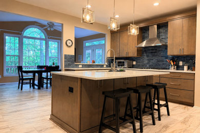 Kitchen - contemporary l-shaped ceramic tile and beige floor kitchen idea in DC Metro with a drop-in sink, flat-panel cabinets, medium tone wood cabinets, quartz countertops, blue backsplash, subway tile backsplash, stainless steel appliances and an island