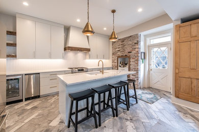 Open concept kitchen - small transitional galley ceramic tile and gray floor open concept kitchen idea in Charleston with flat-panel cabinets, gray cabinets, quartz countertops, glass tile backsplash, stainless steel appliances and an island