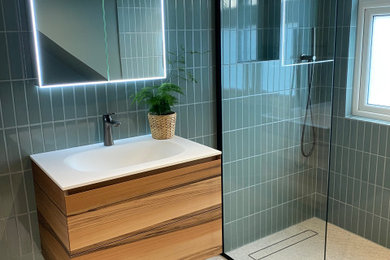 This is an example of a small contemporary bathroom in London with flat-panel cabinets, a walk-in shower, a one-piece toilet, green tiles, ceramic tiles, green walls, porcelain flooring, a built-in sink, grey floors, an open shower, white worktops, a wall niche, a single sink and a floating vanity unit.