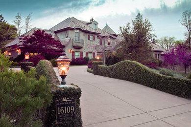 Large traditional gray two-story stucco exterior home idea in Sacramento with a hip roof
