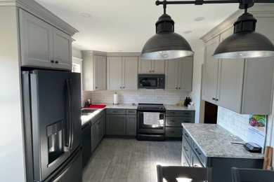 Example of a mid-sized transitional l-shaped vinyl floor and gray floor eat-in kitchen design in Louisville with an undermount sink, recessed-panel cabinets, gray cabinets, quartz countertops, white backsplash, subway tile backsplash, black appliances, no island and gray countertops