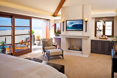This is an example of a contemporary bedroom in Orange County with beige walls, carpet and a standard fireplace.