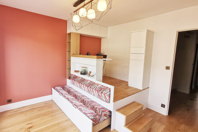 Exemple d'une grande chambre d'amis moderne avec un mur orange, parquet clair, aucune cheminée et un sol marron.