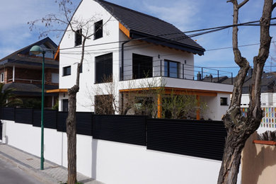 Imagen de fachada de casa blanca y negra escandinava con revestimiento de estuco, tejado a dos aguas, tejado de teja de barro y escaleras