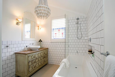 Inspiration for a beach style 3/4 bathroom in Brisbane with an alcove tub, a shower/bathtub combo, white tile, white walls, a vessel sink, an open shower and recessed-panel cabinets.