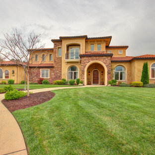 На фото: класса люкс большие, двухэтажные фасады частных домов оранжевого цвета в средиземноморском стиле с облицовкой из цементной штукатурки, вальмовой крышей и черепичной крышей