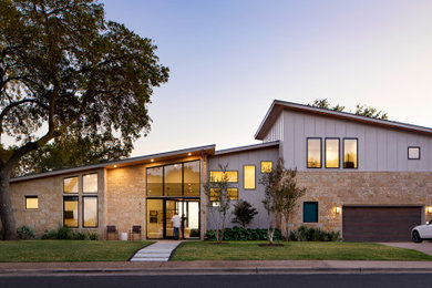 Example of a mid-century modern gray two-story mixed siding and board and batten house exterior design in Austin with a shed roof