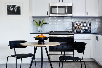 Small minimalist l-shaped vinyl floor and gray floor eat-in kitchen photo in San Francisco with flat-panel cabinets, white cabinets, quartz countertops, blue backsplash, ceramic backsplash, stainless steel appliances, no island and black countertops