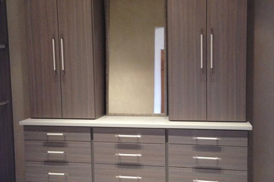 Diseño de armario vestidor unisex contemporáneo de tamaño medio con armarios con paneles lisos, puertas de armario de madera oscura, suelo de baldosas de porcelana y suelo beige