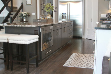 Inspiration for a mid-sized contemporary l-shaped dark wood floor and brown floor open concept kitchen remodel in Milwaukee with an undermount sink, flat-panel cabinets, white cabinets, granite countertops, multicolored backsplash, mosaic tile backsplash, stainless steel appliances and an island