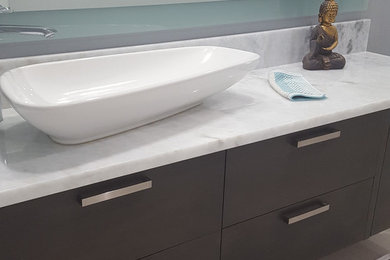 Example of an asian 3/4 porcelain tile and gray floor corner shower design in Miami with flat-panel cabinets, a vessel sink, marble countertops, a hinged shower door and blue walls