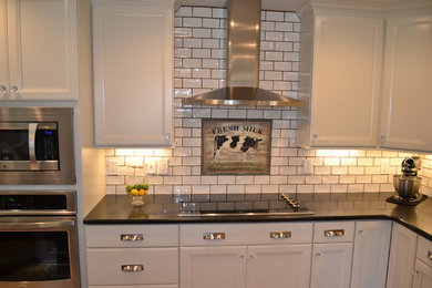 Eat-in kitchen - mid-sized country l-shaped light wood floor and brown floor eat-in kitchen idea in Other with a double-bowl sink, flat-panel cabinets, white cabinets, granite countertops, white backsplash, ceramic backsplash, stainless steel appliances and an island