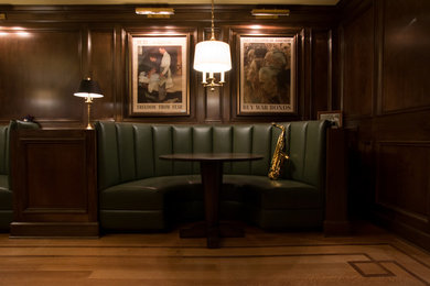 Ejemplo de sala de estar con rincón musical cerrada tradicional grande con paredes marrones, suelo de madera clara y televisor colgado en la pared