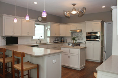 Example of a large classic u-shaped medium tone wood floor eat-in kitchen design in Wichita with an undermount sink, shaker cabinets, gray cabinets, quartz countertops, white backsplash, ceramic backsplash, stainless steel appliances and an island