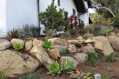 Inspiration for a large mediterranean drought-tolerant and full sun backyard mulch retaining wall landscape in Orange County for summer.