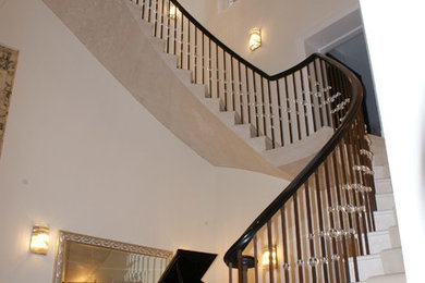Sweeping staircase balustrade in brass, glass and timber.