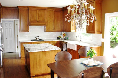 Inspiration for a mid-sized timeless u-shaped medium tone wood floor and brown floor eat-in kitchen remodel in Detroit with a farmhouse sink, beaded inset cabinets, medium tone wood cabinets, granite countertops, white backsplash, ceramic backsplash, stainless steel appliances and an island