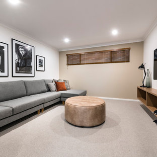 Midcentury modern open concept carpeted and beige floor home theater photo in Perth with beige walls and a wall-mounted tv