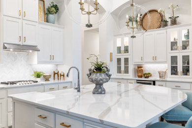 Transitional kitchen photo in Dallas with white cabinets, quartzite countertops and an island