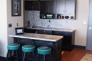 Inspiration for a small contemporary galley open concept kitchen remodel in Huntington with flat-panel cabinets, dark wood cabinets, solid surface countertops, metallic backsplash and glass tile backsplash