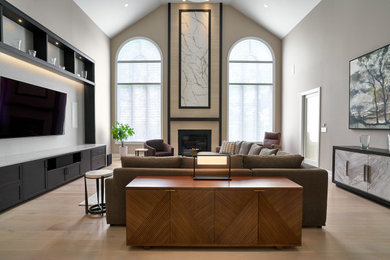 Inspiration for an expansive contemporary enclosed games room in Chicago with beige walls, light hardwood flooring, a standard fireplace, a tiled fireplace surround, a built-in media unit, beige floors and a vaulted ceiling.