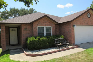 Elegant red one-story brick house exterior photo with a hip roof and a shingle roof