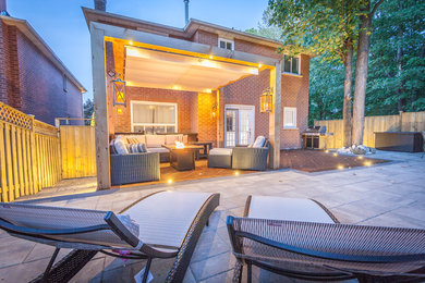 Traditional backyard patio in Toronto with concrete pavers and a pergola.