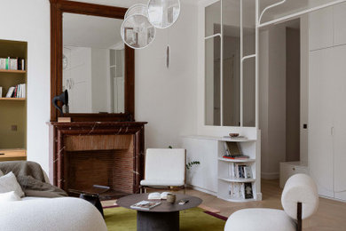 Idée de décoration pour un grand salon design ouvert et haussmannien avec une bibliothèque ou un coin lecture, un mur blanc, parquet clair, une cheminée standard, un manteau de cheminée en pierre et aucun téléviseur.