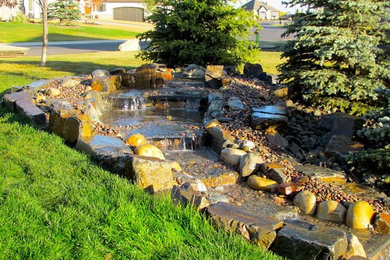 Photo of a mid-sized traditional backyard partial sun garden in Edmonton with a water feature and natural stone pavers.