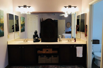 Example of a large classic master dark wood floor and brown floor bathroom design in Other with flat-panel cabinets, dark wood cabinets, a two-piece toilet, white walls, a drop-in sink, solid surface countertops and beige countertops