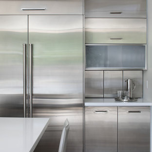 Inspiration pour une arrière-cuisine design en L de taille moyenne avec un placard à porte plane, une façade en inox, un plan de travail en quartz modifié, une crédence métallisée, une crédence en dalle métallique, un électroménager en acier inoxydable, un sol en bois clair, un îlot central et un plan de travail blanc.