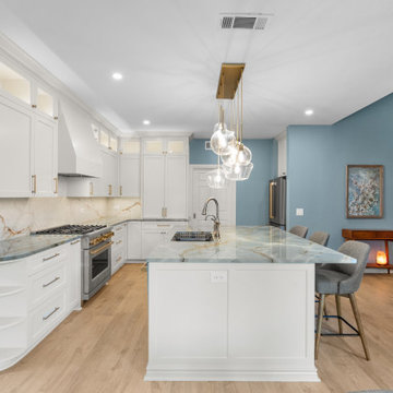 Wide-angle open concept kitchen with steel blue accent walls and a dramatic quar