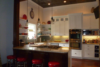 Eat-in kitchen - small eclectic u-shaped medium tone wood floor eat-in kitchen idea in Nashville with a farmhouse sink, recessed-panel cabinets, white cabinets, granite countertops, blue backsplash, glass tile backsplash, stainless steel appliances and a peninsula