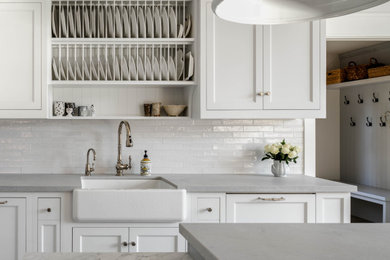 Example of a large transitional l-shaped light wood floor and brown floor eat-in kitchen design in Toronto with a farmhouse sink, recessed-panel cabinets, white cabinets, marble countertops, white backsplash, subway tile backsplash, stainless steel appliances, an island and gray countertops