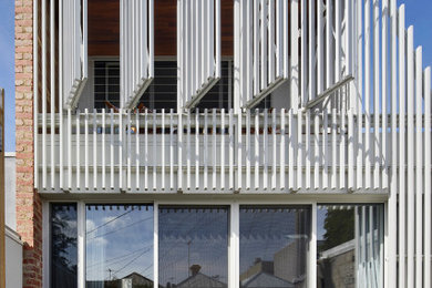 Mid-sized contemporary two-storey white house exterior in Melbourne with metal siding, a flat roof, a metal roof and a white roof.