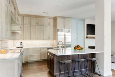 Inspiration for a large transitional l-shaped eat-in kitchen in Dallas with an undermount sink, recessed-panel cabinets, light wood cabinets, quartz benchtops, beige splashback, ceramic splashback, stainless steel appliances, medium hardwood floors, with island, brown floor and white benchtop.